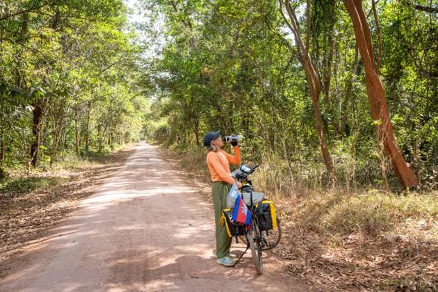 Woman traveling on her bicycle loaded with bags, drinks water on Krong Poi Pet, Banteay Meanchey Province, Cambodia R_SIIZ23082952-1243825-01 ,model released, Symbolfoto