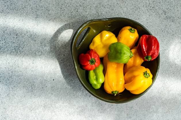 Top view of different colored peppers placed in a round black ceramic bowl on a concrete background Model Released AnnaBogush_ID16232_493838_003 Copyright: xAnnaxBogushx
