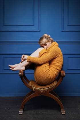 Creative Highlights Symbolfotos Young woman curled up in an old armchair Studio portrait of a barefoot young woman in yellow pullover curling up in an old armchair on blue wall background. ,model released, Symbolfoto Copyright: xZoonar.com OleksandrxBerezkox 17857905 ,model released, Symbolfoto ,property released