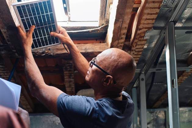 Construction worker examining solar panel over window in attic model released, Symbolfoto property released, ASGF04406