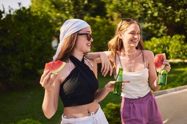 Happy woman with friend holding bottle and watermelon on sunny day model released, Symbolfoto property released, ANNF00409