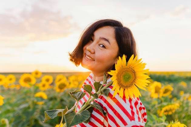 Creative Highlights Symbolbilder Mature smiling woman with sunflower at sunset model released, Symbolfoto, IEF00519