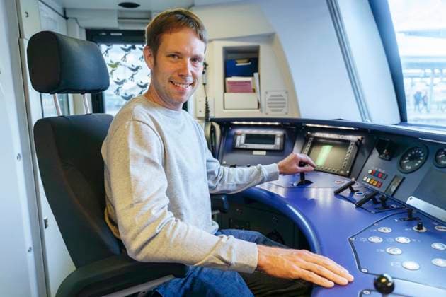 Happy man sitting in cockpit of train engine model released, Symbolfoto, NJAF00542