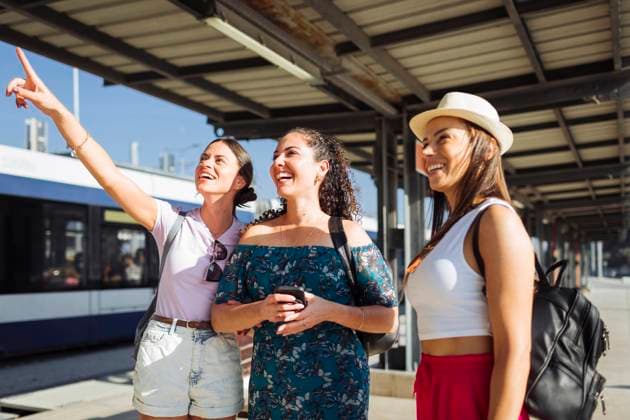 Happy woman gesturing and standing with friends at railroad station platform model released, Symbolfoto, DCRF01815