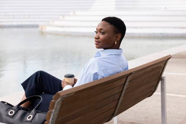Smiling businesswoman sitting with coffee cup on bench model released, Symbolfoto, JPTF01297