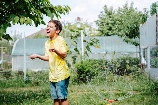IMAGO Creative: Sommer, Sommertage im Garten Happy boy playing with water splashing from hose model released, Symbolfoto, NLAF00145