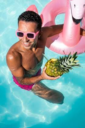 Happy man holding pineapple and swimming in water model released, Symbolfoto, VRAF00193
