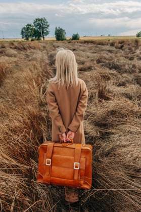 Blond woman walking with suitcase in field model released, Symbolfoto, VSNF01290