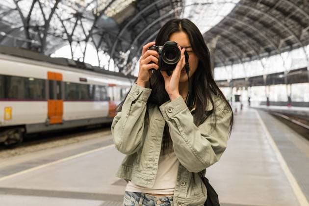 Female photographer taking a picture with a camera in a train station. Barcelona, Catalonia, Spain CR_ZVWBHP230921-1247402-01 ,model released, Symbolfoto