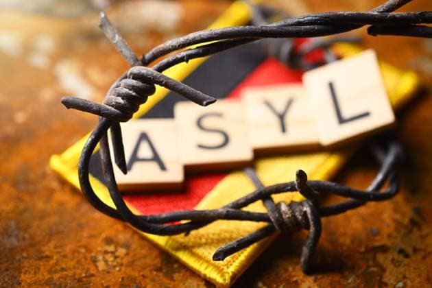 Schriftzug Asyl auf Fahne von Deutschland mit Stacheldraht, Symbolfoto Migrationskrise *** Writing asylum on flag of Germany with barbed wire, symbol photo migration crisis ** NUR FUER REDAKTIONELLE ZWECKE ** EDITORIAL USE ONLY **