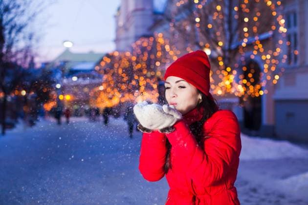 Young girl blowing away snow from mittens Outdoor photo of young beautiful girl blowing away snow from her warm white mittens, posing in street with Christmas lights on trees on background ,model released, Symbolfoto Copyright: xZoonar.com OksanaxShufrychx 14331298 ,model released, Symbolfoto ,property released