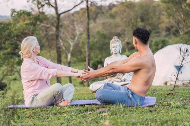 PR_ID16198_4588_GlampingCabins.jpg, MR_ID16198_14968_PatriciaSas.jpg, MR_ID16198_14967_FedericoOmarStein.jpg Side view of male and female holding hands while sitting on mat in lotus pose near Buddha statue together, Property released Model Released ReneStevens_ID16198_492603_034 Copyright: xRenexStevensx
