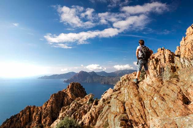 Ein Wanderer steht in der Calanche einer bizarre Felsenlandschaft an der Suedkueste des Golfs von Porto im Regionalen Naturpark Korsika auf einem Felsen und schaut auf das Meer Korsika Frankreich Europa *** a Hikers is in the Calanche a Bizarre Rocky Landscape to the South Coast of Golfs from Porto at regional Nature Park Corsica at a Rocks and looks at the Sea Corsica France Europe Copyright: imageBROKER ThomasxHeitz ibxtsh09681766.jpg ,model released, Symbolfoto ,property released