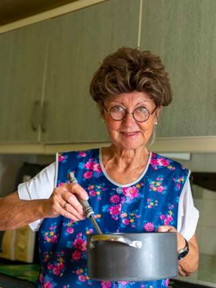 Grandma with Age Smock apron, Glasses and Wig in the Kitchen, holds Cooking pot and Kelle in Hands, Germany, Europe Copyright: imageBROKER/BerndxBieder ibxbmb09698243.jpg ,model released, Symbolfoto ,property released