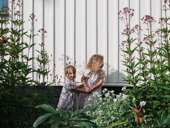 older sister holding her younger sisters hand through the flowers Stockholm, Stockholm County, Sweden CR_RABE231011-1262048-01 ,model released, Symbolfoto
