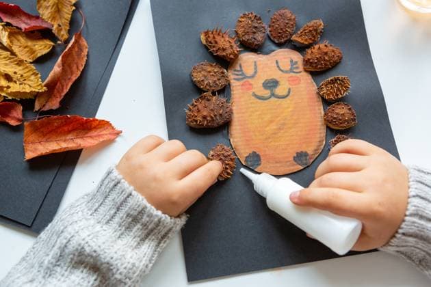 6 October 2023: Children s fun with autumn leaves: creative crafts at home. A child makes a collage of a hedgehog. Hands glue leaves and chestnut shells from the picture *** Kinderspaß mit Herbstlaub: Kreatives Basteln zu Hause. Ein Kind bastelt eine Kollage von einem Igel. Hände kleben Laub und Kastanien Schalen aus das Bild