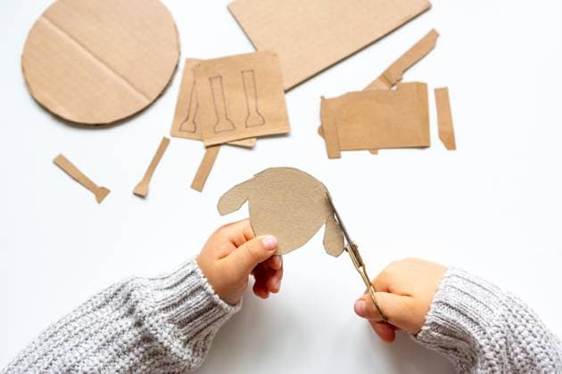 6 October 2023: Creative crafts at home in autumn. A child cuts parts for a sheep from a cardboard box with scissors *** Kreatives Basteln zu Hause im Herbst. Ein Kind schneidet mit einer Schere teile für ein Schaf aus einem Karton