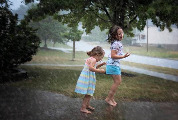 Sisters jumping in puddles during summer rain Wooster, Ohio, United States CR_JOKU231022-1268193-01 ,model released, Symbolfoto