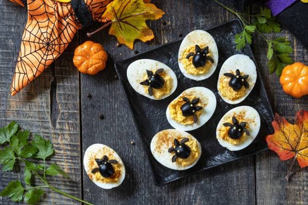 Halloween funny idea for party food. Halloween creative set stuffed eggs with paprica and bat on a wooden table. Top view flat lay background. Halloween funny idea for party food. Halloween creative set stuffed eggs with paprica and bat on a wooden table. Top view flat lay background. Copyright: xZoonar.com ELENAxHRAMOVAx 20597888