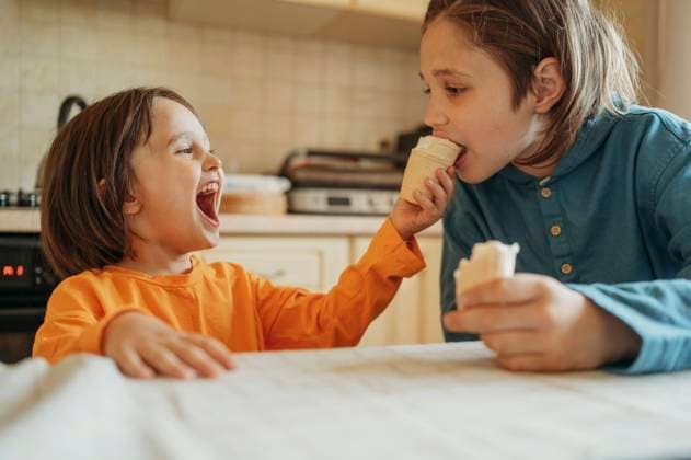 Happy boy feeding ice cream to brother at home model released, Symbolfoto property released, ANAF01484