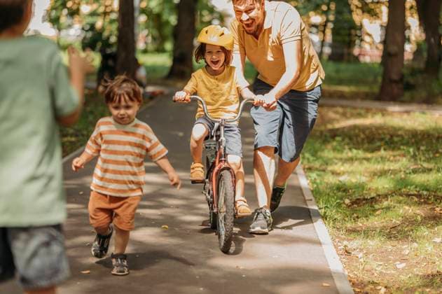 Father assisting son riding bicycle on footpath at park model released, Symbolfoto, ANAF01826