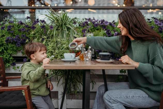Happy boy with mother serving tea in cup at cafe model released, Symbolfoto, ANAF02122