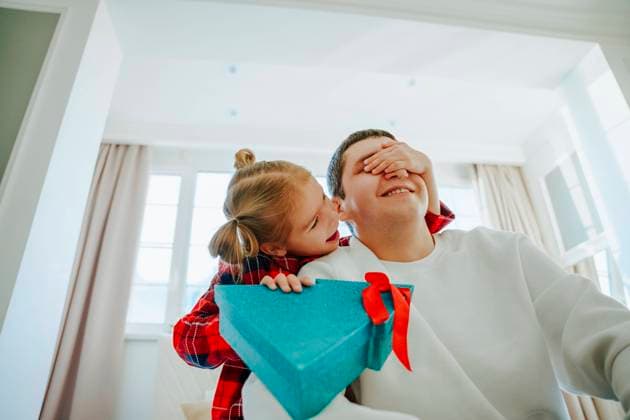 Smiling daughter holding Christmas present and covering father s eyes at home model released, Symbolfoto property released, NLAF00112