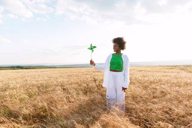 Young woman with pinwheel toy standing in field model released, Symbolfoto, AAZF01040