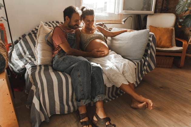 Happy man with pregnant woman sitting on sofa at home model released, Symbolfoto property released, PCLF00727