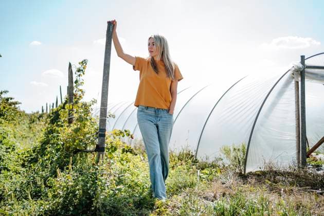 Blond woman standing near green house in raspberry field model released, Symbolfoto, MDOF01532