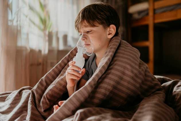 Elementary boy inhaling through nebulizer at home model released, Symbolfoto property released, ANAF02222