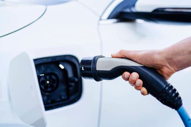 Woman plugging charger in electric car at station model released, Symbolfoto property released, DIGF20872