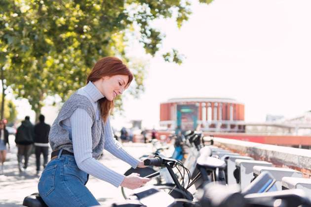 Smiling woman renting electric bicycle through smart phone app model released, Symbolfoto, PNAF05920