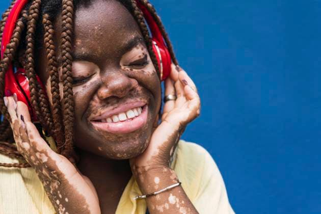 Smiling young woman wearing wireless headphones against blue background model released, Symbolfoto, PNAF06057