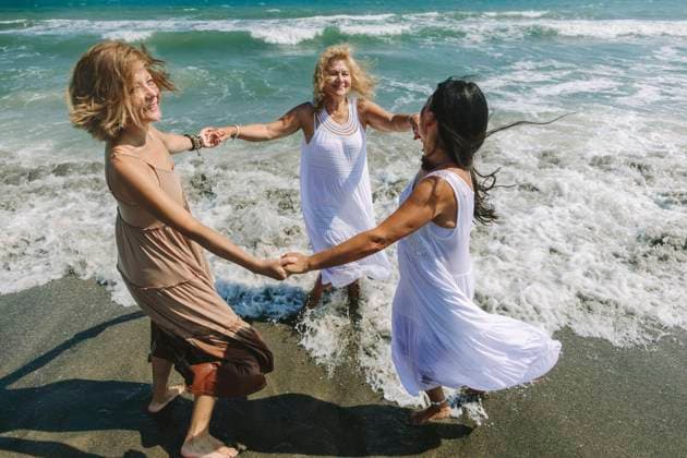 Cheerful friends holding hands and playing ring around the rosy near sea at beach model released, Symbolfoto, SIF00938