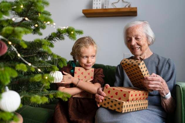 Happy granddaughter with grandmother holding gifts near Christmas tree at home model released, Symbolfoto property released, SVKF01610