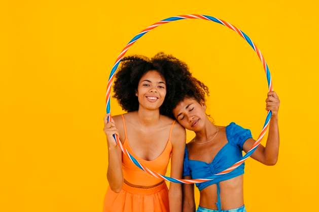 Woman leaning on friend holding plastic hoop against yellow background model released, Symbolfoto, TCEF02315