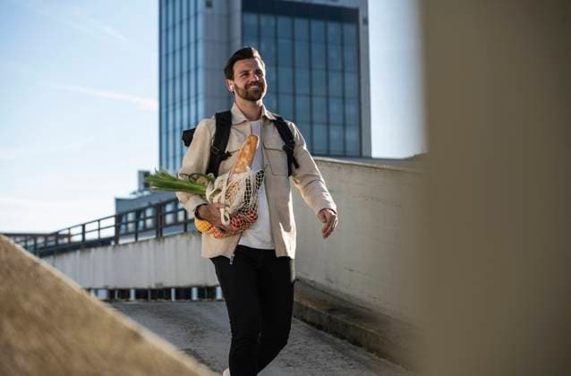 Smiling man walking with bag of groceries in front of building model released, Symbolfoto, UUF30503