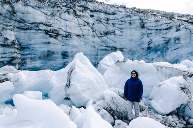 An individual clad in a blue jacket stands among towering ice formations, with the intricate patterns of a glacier wall serving as a backdrop. Model Released JuanAizpuru_ID16340_497318_009 Copyright: xJuanxAizpurux RECORD DATE NOT STATED