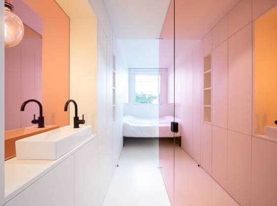 A stylish bathroom area with dual sinks against a backdrop of gradient colored walls transitioning from pink to orange, leading to a bedroom view. Model Released RubenPb_ID13936_420115_006 Copyright: xRubenxPbx RECORD DATE NOT STATED