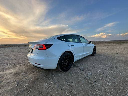 RECORD DATE NOT STATED A white Tesla model 3 parked outdoors at sunset 21723182