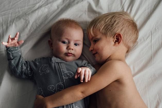 Overhead close up of toddler cuddling baby on bed while baby loo United States, North Dakota, Bismarck CR_KIFR231113-1286831-01 ,model released, Symbolfoto