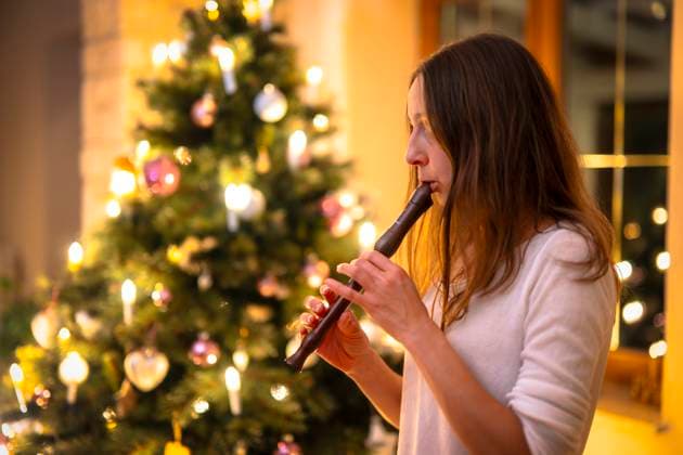 15 11 2023, Christmas 2023 in Germany, A festively decorated Christmas tree in an apartment in Unterallgäu A woman plays the recorder in the living room on Christmas Eve Modelreleased 15 11 2023, Christmas tree 15 11 2023, Christmas tree