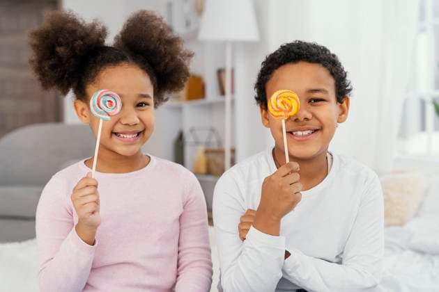 Creative Highlights Symbolbilder Vorderansicht zwei lächelnde Geschwister, die mit Lollipops posieren *** Front view Two smiling Siblings, the with Lollipops pose Copyright: imageBROKER OleksandrxLatkun iblole09800866.jpg ,model released, Symbolfoto ,property released