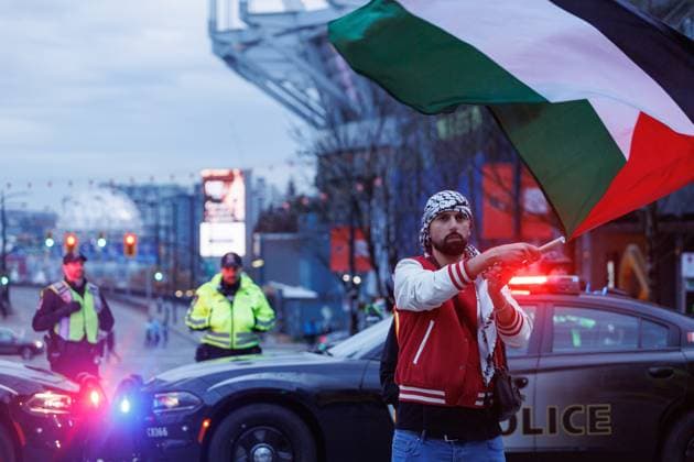 November 18, 2023, Vancouver, British Columbia, Canada: A person waves a Palestinian flag in front of a barricade of Vancouver Police..Thousands of people gather to demand a ceasefire in Gaza at the Vancouver Art Gallery before marching down Georgia Street in Vancouver, British Columbia. Vancouver Canada - ZUMAw171 20231118_znp_w171_008 Copyright: xRyanxWalterxWagnerx