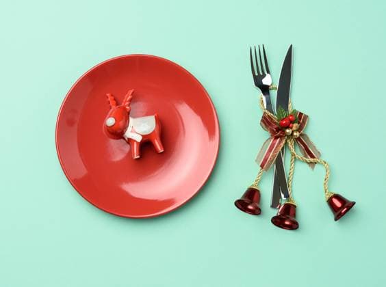 round red ceramic plate, knife and fork on green background, festive table setting round red ceramic plate, knife and fork on green background, festive table setting for christmas and new year, top view Copyright: xZoonar.com DankoxNatalyax 16343397