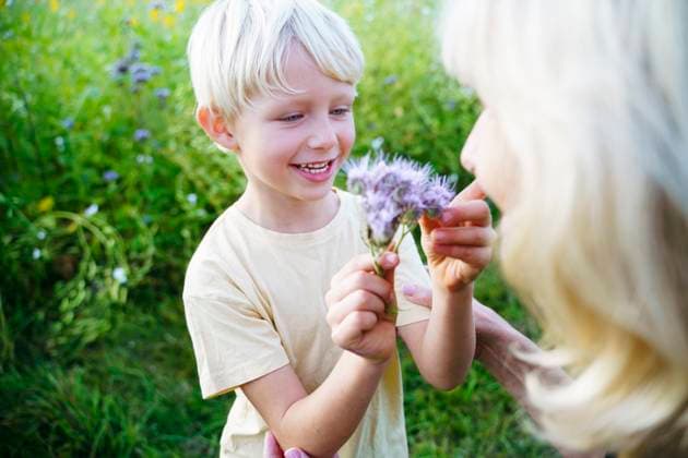 Creative Highlights Symbolbilder Smiling grandson looking at flower with grandmother in field model released, Symbolfoto, NJAF00600
