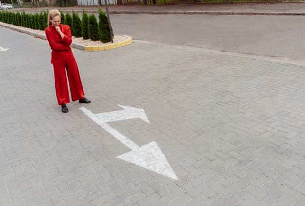 Thoughtful woman with hand on chin standing near arrow sign at street model released, Symbolfoto, OSF02315