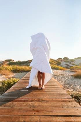 Creative Highlights Symbolbilder Woman covered in blanket standing on boardwalk at beach model released, Symbolfoto, SIF01062