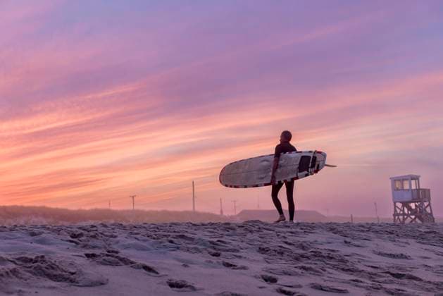 A surfer walks on the beach with his surfboard at sunset Orleans, Massachusetts, United States CR_JUCU231129F1-1272598-01 ,model released, Symbolfoto